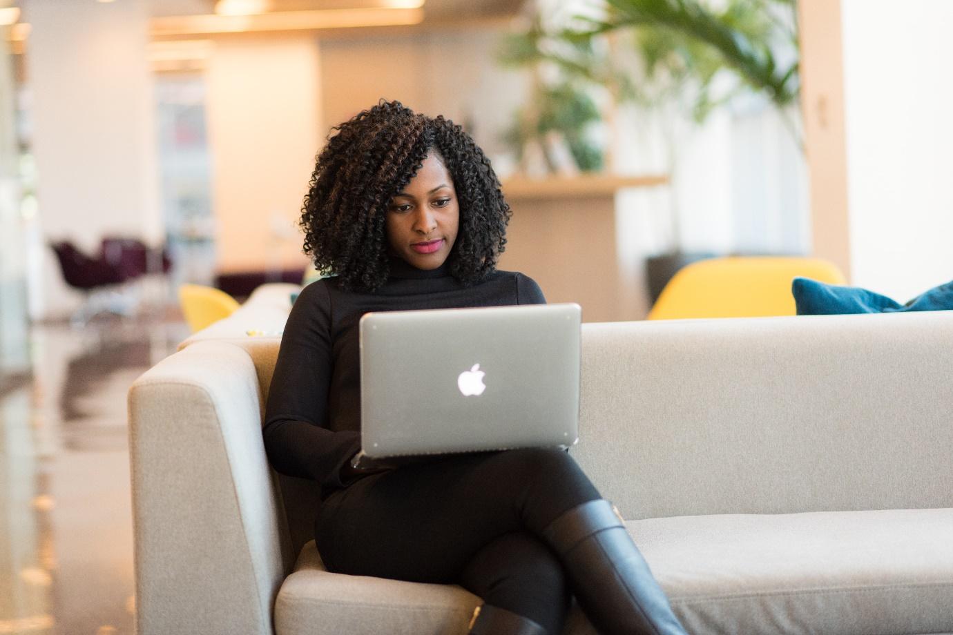 A person sitting on a couch using a computer Description automatically generated