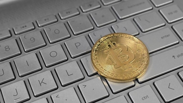 A gold-colored bitcoin token resting on a laptop keyboard