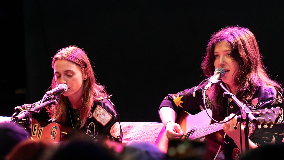Julien Baker and Lucy Dacus playing acoustic guitars and singing on stage