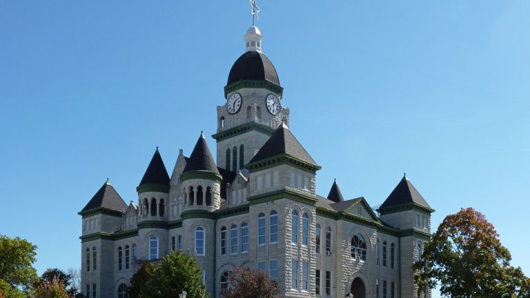 The turreted stone Jasper County Courthouse in Carthage, Missouri, under a blue sky