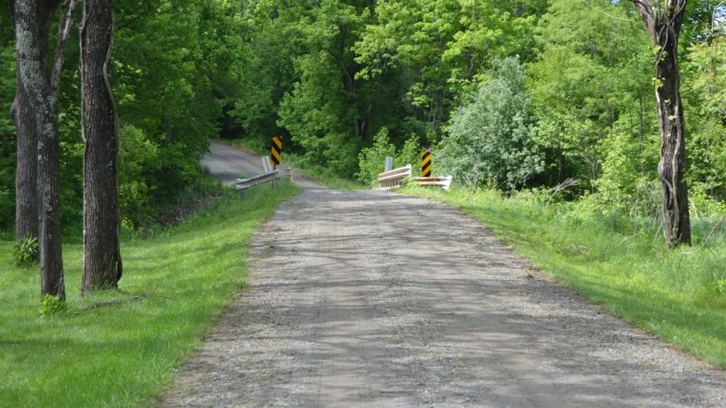 A graded gravel road leading to a small bridge in rural Virginia
