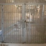 A barred cell door inside an old prison cell block