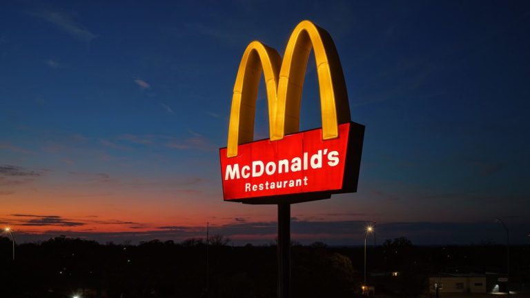A McDonald's golden arches sign lit against an evening sky