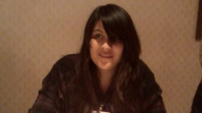 Bee and PuppyCat creator Natasha Allegri seated at a table at a fan convention