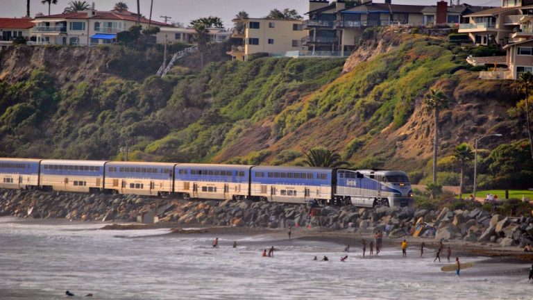 Homes on a coastal bluff above a passenger train and beach in San Clemente, California