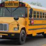 A yellow school bus with its stop sign arm folded in, parked on a two-lane road in Virginia