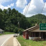 Utility lines run along Virginia Route 352 at Stone Creek in Lee County, beside a road sign pointing to St. Charles and Bonny Blue, with forested hills behind