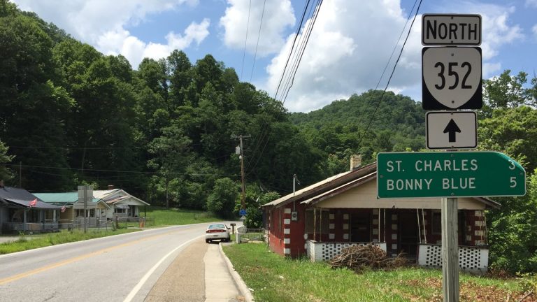 Utility lines run along Virginia Route 352 at Stone Creek in Lee County, beside a road sign pointing to St. Charles and Bonny Blue, with forested hills behind