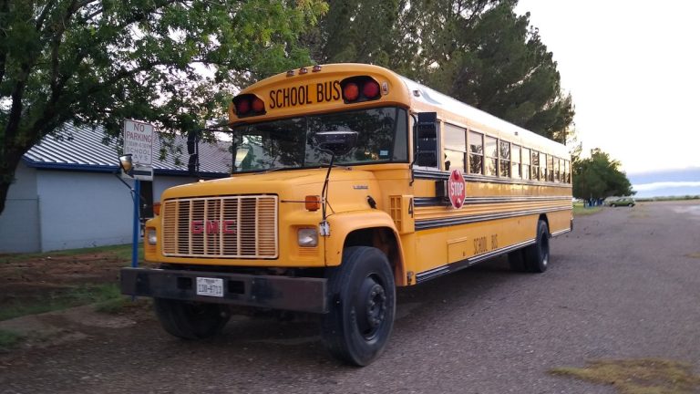 A yellow school bus parked outside a school in Dell City, Texas
