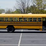 A yellow Virginia school bus parked by a building