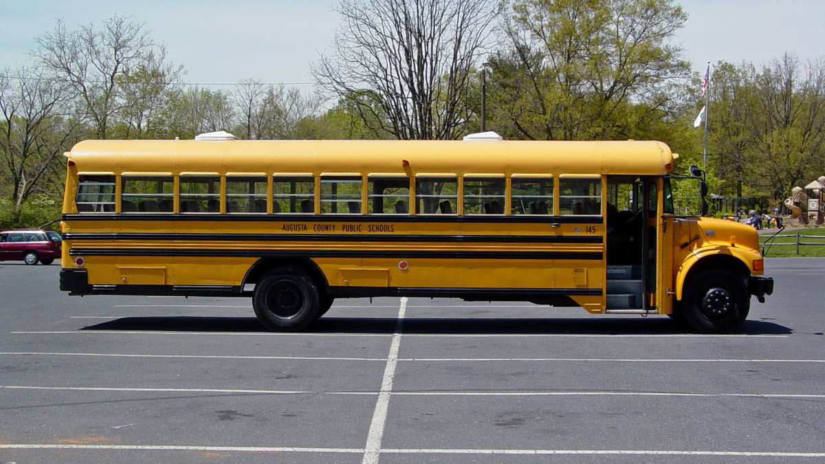 A yellow Virginia school bus parked by a building