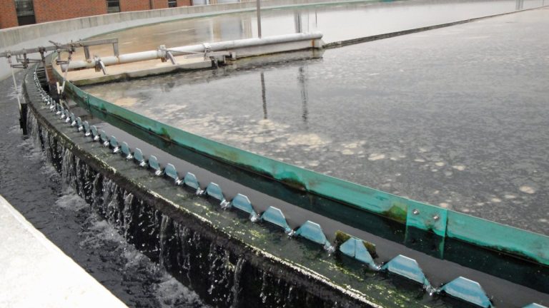 Water spilling over the edge of a round clarifier tank at a wastewater treatment plant